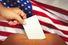 Close up of a hand placing a ballot in a ballot box. Election vote voter voting