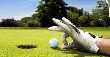 golf. Competitive and cheating golfer wears golf gloves on golf club greens and prepares golf ball for lucky hole in one. Unsportsmanlike, sports, cheater