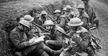 British troops in a trench on the Western front during World War I. One officer takes reports of the fighting over a field telephone while the officer on the left jots it down and issues new orders.