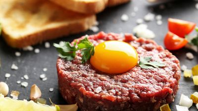 Steak tartare with raw egg on top. Steak tartare is a dish made with raw ground beef