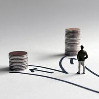 A miniature man standing in front of two paths leading to stacks of coins of different heights.