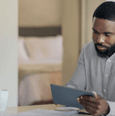 A man is looking at his tablet at the kitchen counter. 