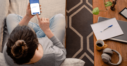 A woman uses a financing app while sitting on her couch.