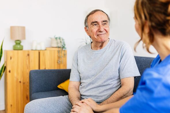 Female caregiver talking with senior male patient at nursing home.