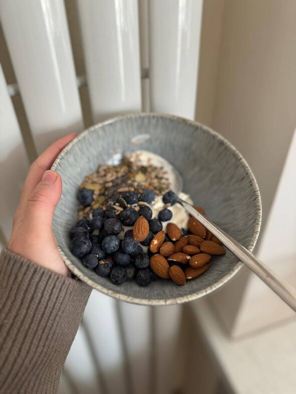 A bowl of yoghurt, nuts, seeds and blueberries