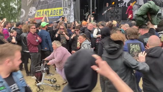 Elderly woman with walker leads mosh pit at heavy metal music festival