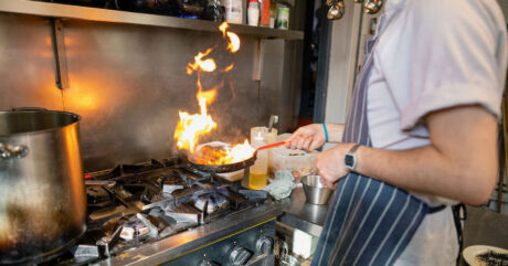 Chef in a restaurant kitchen cooking using gas