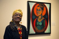 Artist Faith Ringgold poses for a portrait in front of a painted self-portrait during a press preview of her exhibition, "American People, Black Light: Faith Ringgold's Paintings of the 1960s" at the National Museum of Women in the Arts in Washington, June 19, 2013. (AP Photo/Jacquelyn Martin, File)