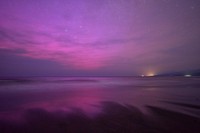 The Sea of Okhotsk reflects the pink hue of an aurora in this photo taken with a 20-second exposure in Shari, Hokkaido, at 11:34 p.m. on May 11, 2024. Pictured to the right is the Shiretoko Peninsula. (Mainichi/Taichi Kaizuka)