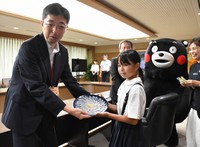 Karin Tabira, right, the youngest person in Japan to obtain certification to prepare fugu, hands over sashimi she prepared to Kumamoto Gov. Takashi Kimura, left, at the Kumamoto Prefectural Government office building in Kumamoto's Chuo Ward on Aug. 22, 2024. (Mainichi/Keiko Yamaguchi)