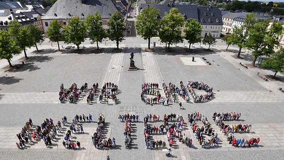 Schüler des Gymnasiums Marienberg und Bürger der Stadt bilden am Nachmittag den Schriftzug "Wir sind Welterbe" auf dem Marktplatz in Marienberg. 