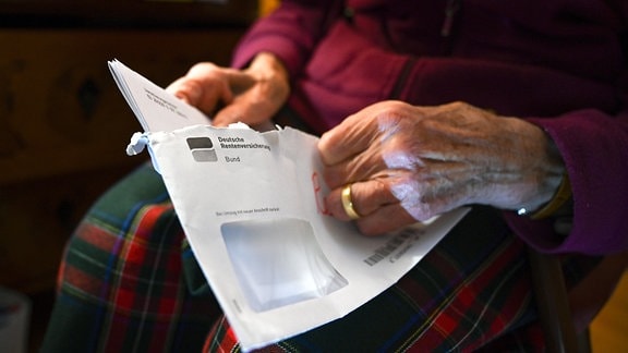 Eine Seniorin hält ihren Rentenbescheid in der Hand