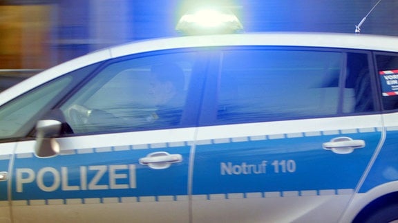 Einsatzwagen der Polizei mit eingeschaltetem Blaulicht, unterwegs.