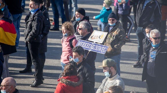 Menschen demonstrieren, eine Frau hält ein Schild mit der Aufschrift "Merkel muss weg".