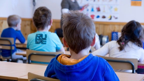 Blick in eine Schulklasse über die Schultern einiger Kinder hinweg