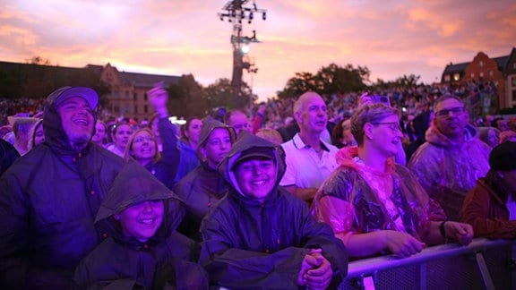 Besucherinnen und Besucher mit Regencapes.