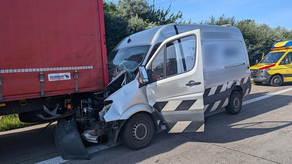 Die Vorderseite eines Transporters ist unter einem Lkw eingeklemmt