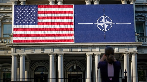 Eine Passantin fotografiert am Eisenhower Building die Fassade mit der US-amerikanischen und der Nato-Flagge. 