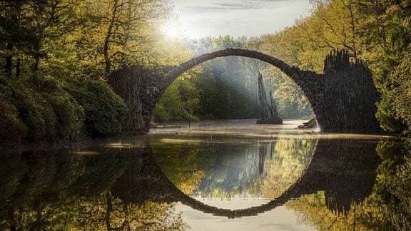 Die Rakotzbrücke im Kromlauer Park: Die 20 Meter lange Brücke spannt sich über das Gewässer in einer runden Krümmung, dass sie mit ihrem Spiegelbild im Wasser einen Kreis ergibt. 