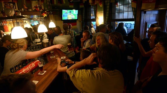 Fußball-Fans schauen in einer Kneipe ein Spiel.