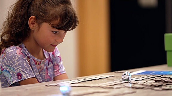 Kind mit Spielzeugroboter auf dem Tisch