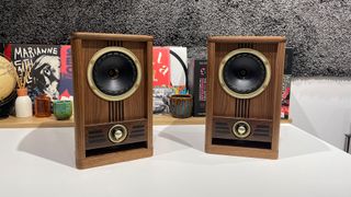 Fyne Vintage Five standmount speakers on white table in front of busy shelf