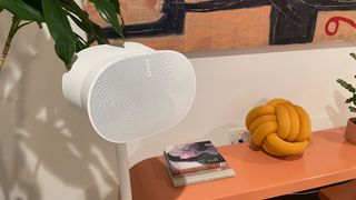 A white Sonos Era 300 speaker on its stand next to a wooden countertop.