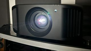 JVC DLA-NZ800 projector with a light coming from the lens in a dark room