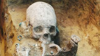 Upper part of the body in Grave 43, during excavation. The girl had an artificially deformed skull; she was buried with a necklace, earrings, a comb and glass beads.