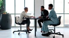 A bank employee sits at a table with a couple at a financial institution.