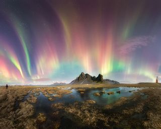 Colorful aurora over a mountain in the distance.
