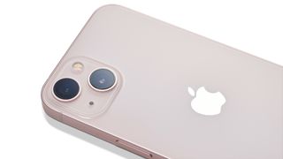 The back of a pink Apple iPhone 13 lying on a white background.