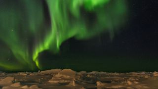 Northern lights over the shore of the frozen Disko Bay in West Greenland. The icefjord nearby is listed as UNESCO world heritage.