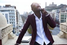 Young entreprenuer takes a business call on the roof deck of his hotel.