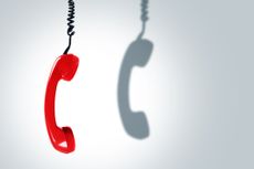 red corded phone dangling with shadow on white backdrop