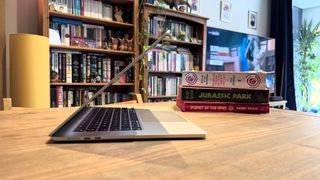 The 2024 MacBook Air M3 on a wooden table in front of a bookshelf.