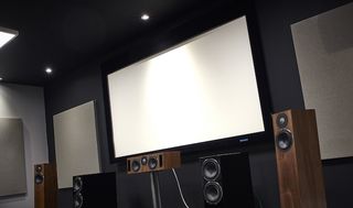 A projector screen on the wall, with a speaker package