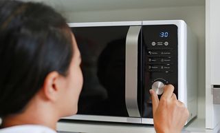 A person using a microwave oven.