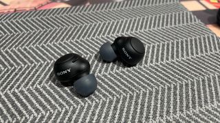 Sony WF-C500 wireless earbuds on a textured surface