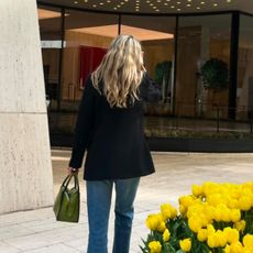 Eliza Huber wearing a black Liberowe blazer and blue Levi's 501 jeans with a green Prada bag.