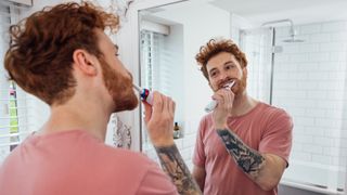 A man brushing his teeth with an electric toothbrush