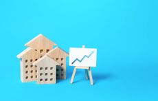 Wooden houses with graph that shows upward trend on a blue background