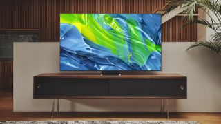 A 4K TV displaying a blue and green wave graphic, sat on a TV console