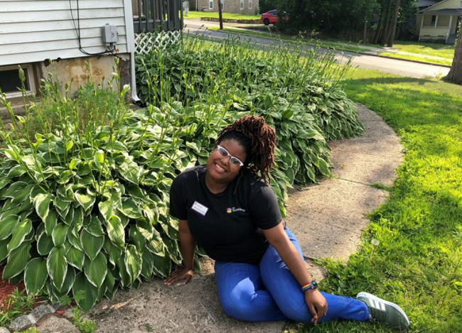 a young woman sitting in the garden of her new home, a multi-family house in Stamford, Connecticut. 