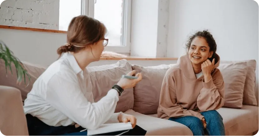 Teen and adult sitting facing each other on couch