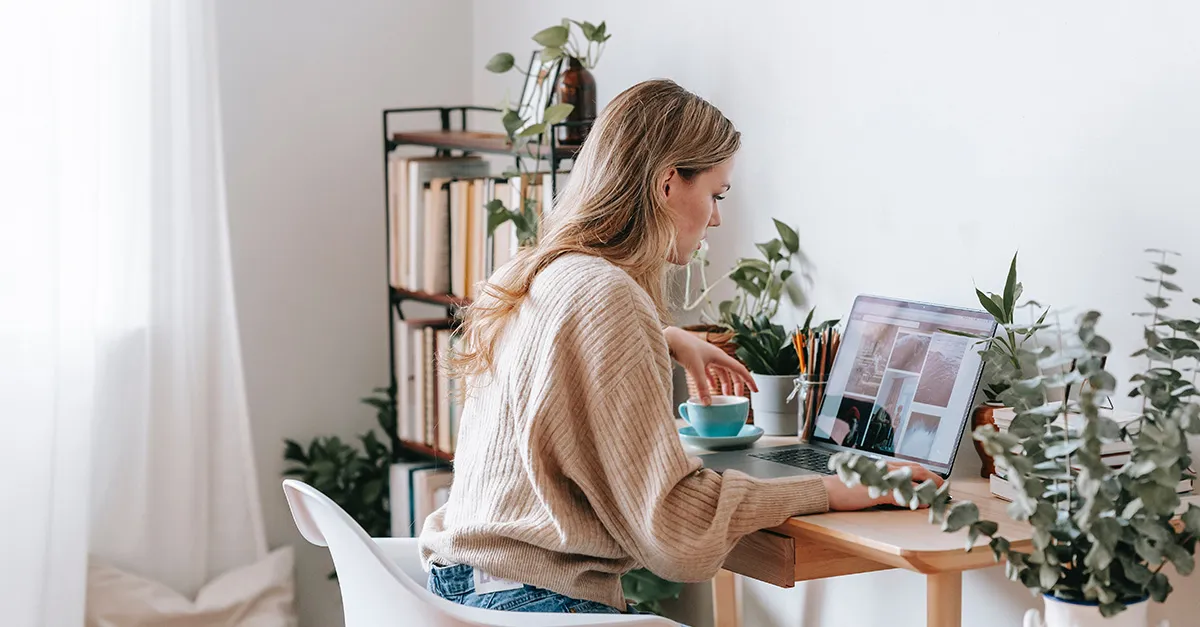 Femme assise à un bureau et naviguant sur son ordinateur portable 