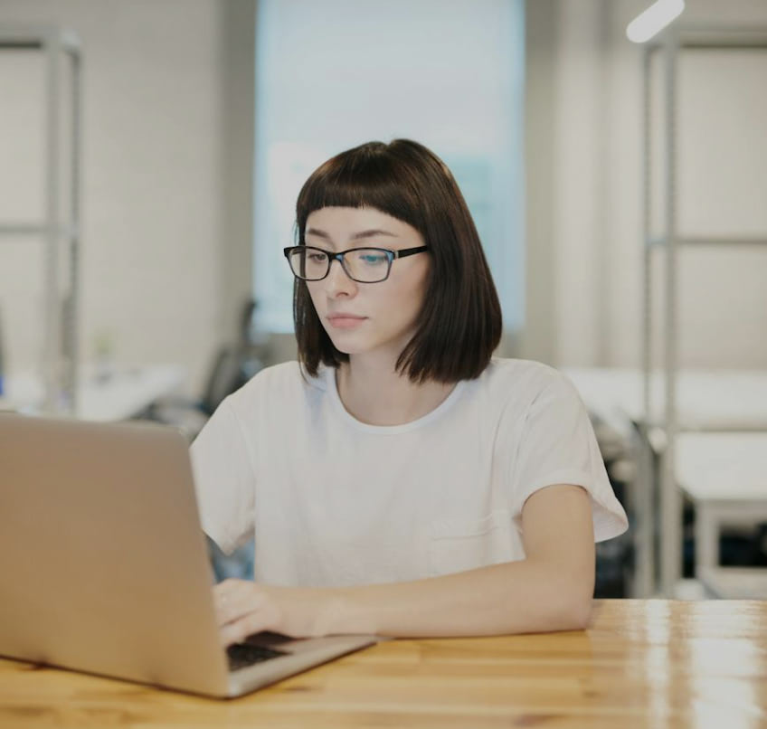 A woman sitting at a table using a laptop computer.