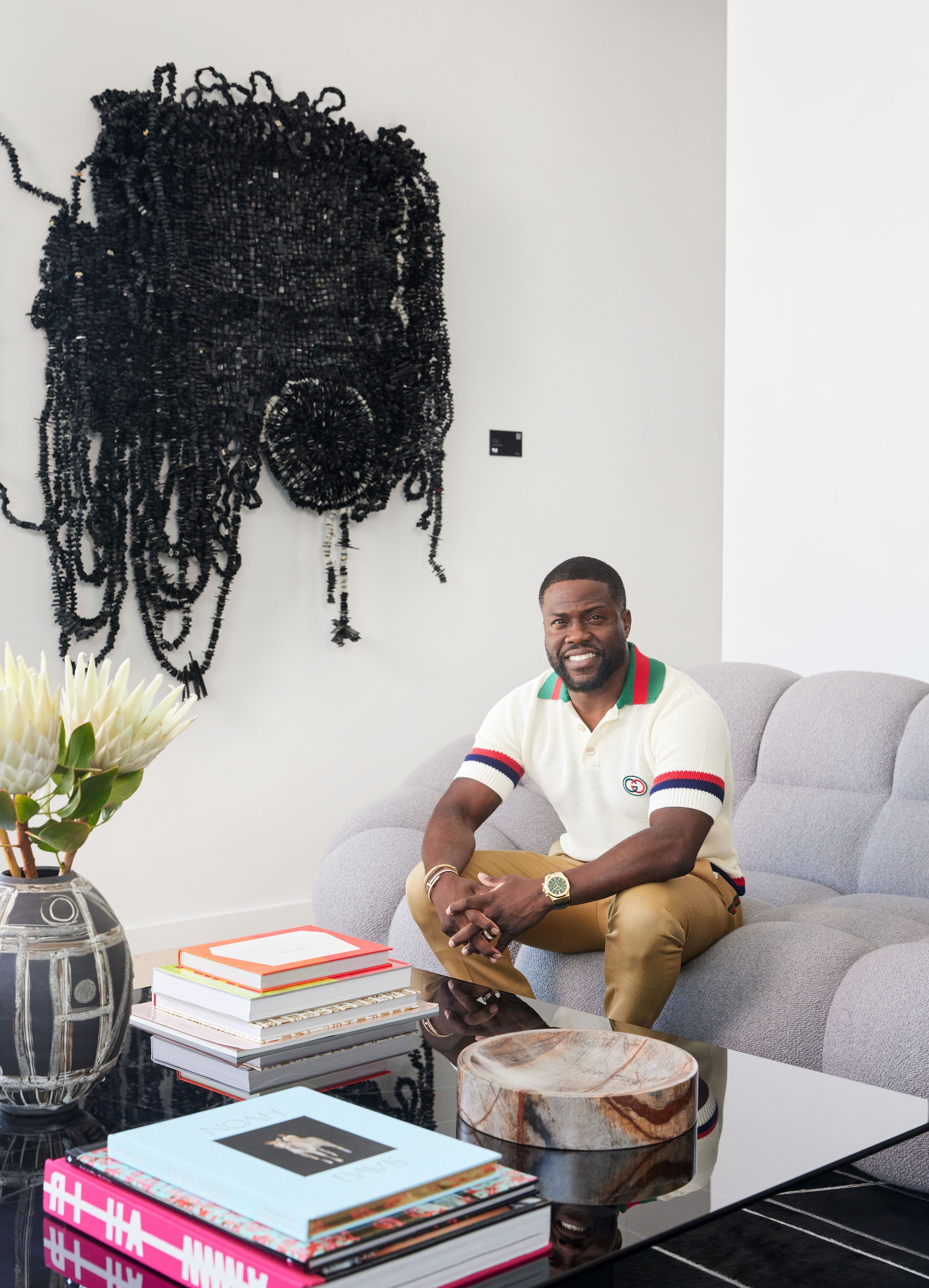 Kevin Hart sitting on a couch in front of an artwork in his offices