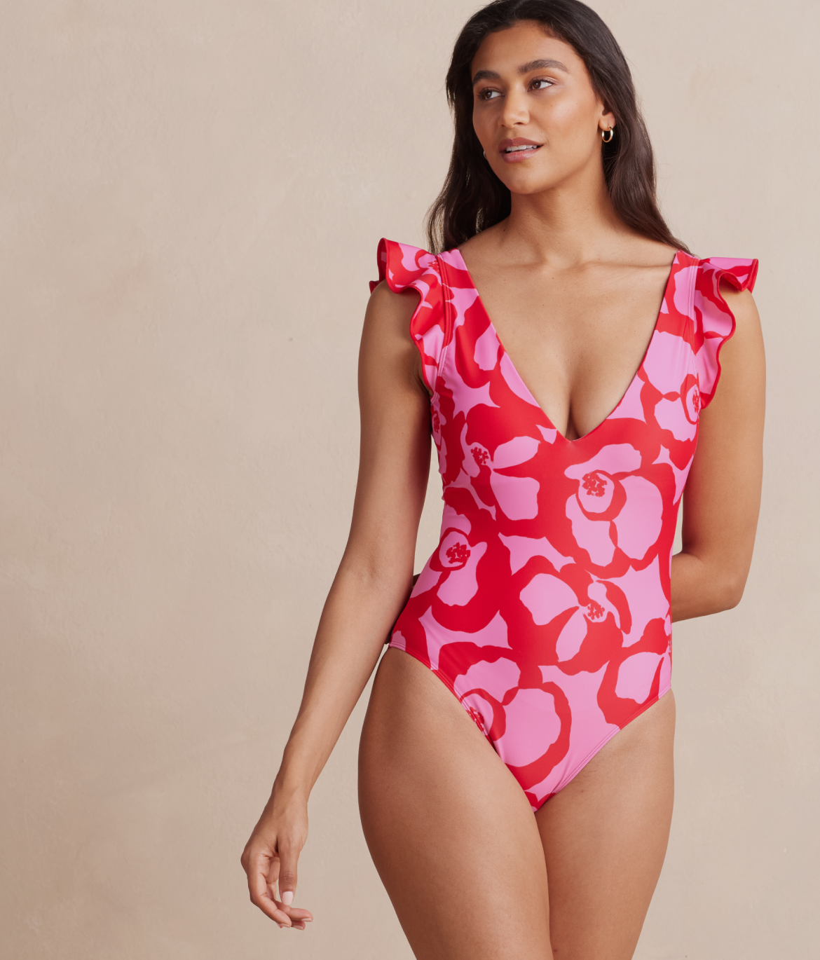 Model in one piece swimsuit, The Ruffle Backflip - Pop Floral in Lava (Pink & Red floral print)