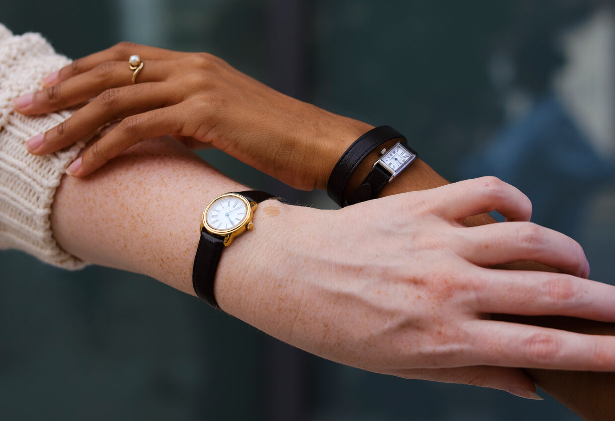 silver kimsey watch and gold harriet watch on intertwining hands